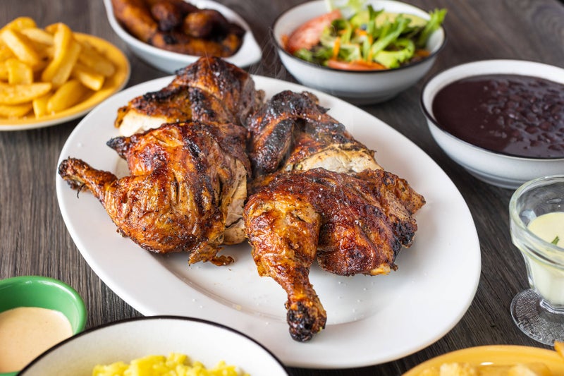 Whole Chicken served on a plate with beans, fries and salad on the side